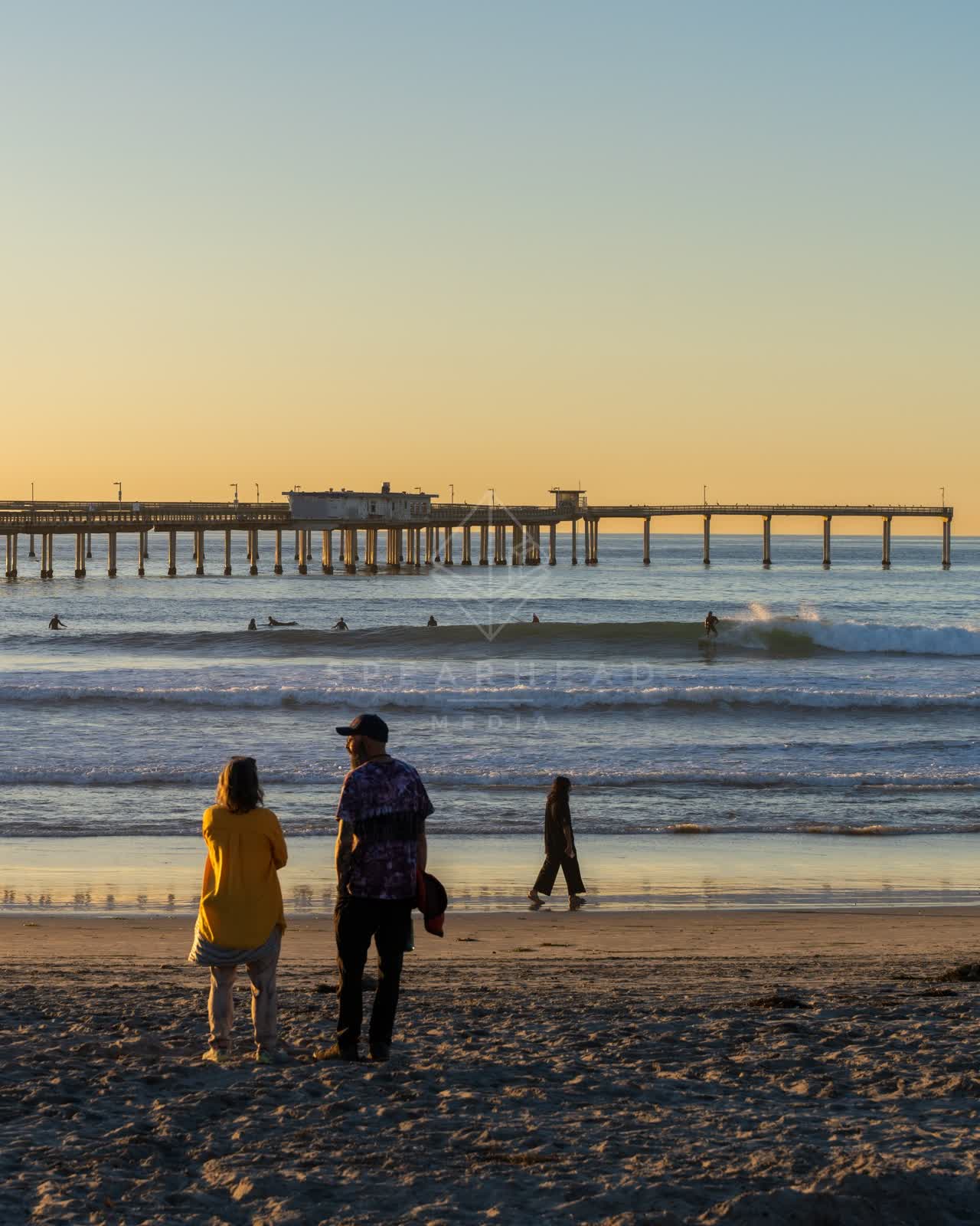 The beach, the surf and the pier in Ocean Beach, with people walking.