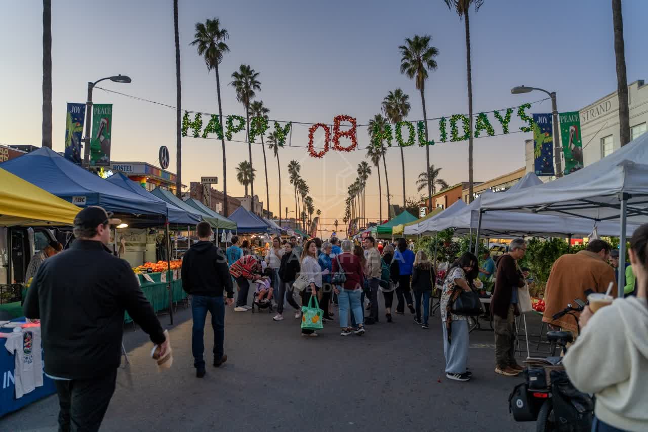 The downtown streets, palm trees and the city in Ocean Beach, with a crowd gathered.