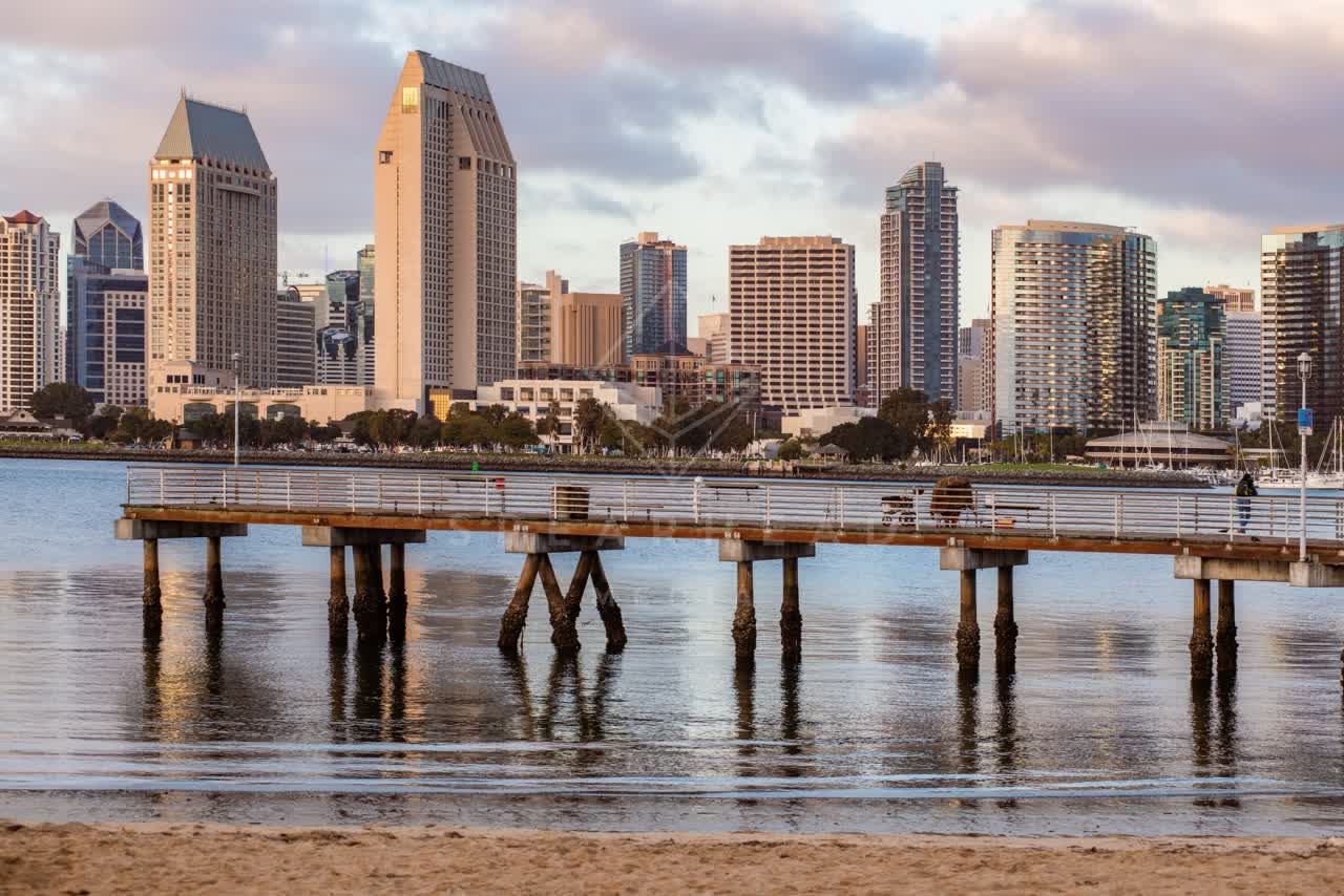 The beach, the pier and the skyline at Embarcadero, with people walking.