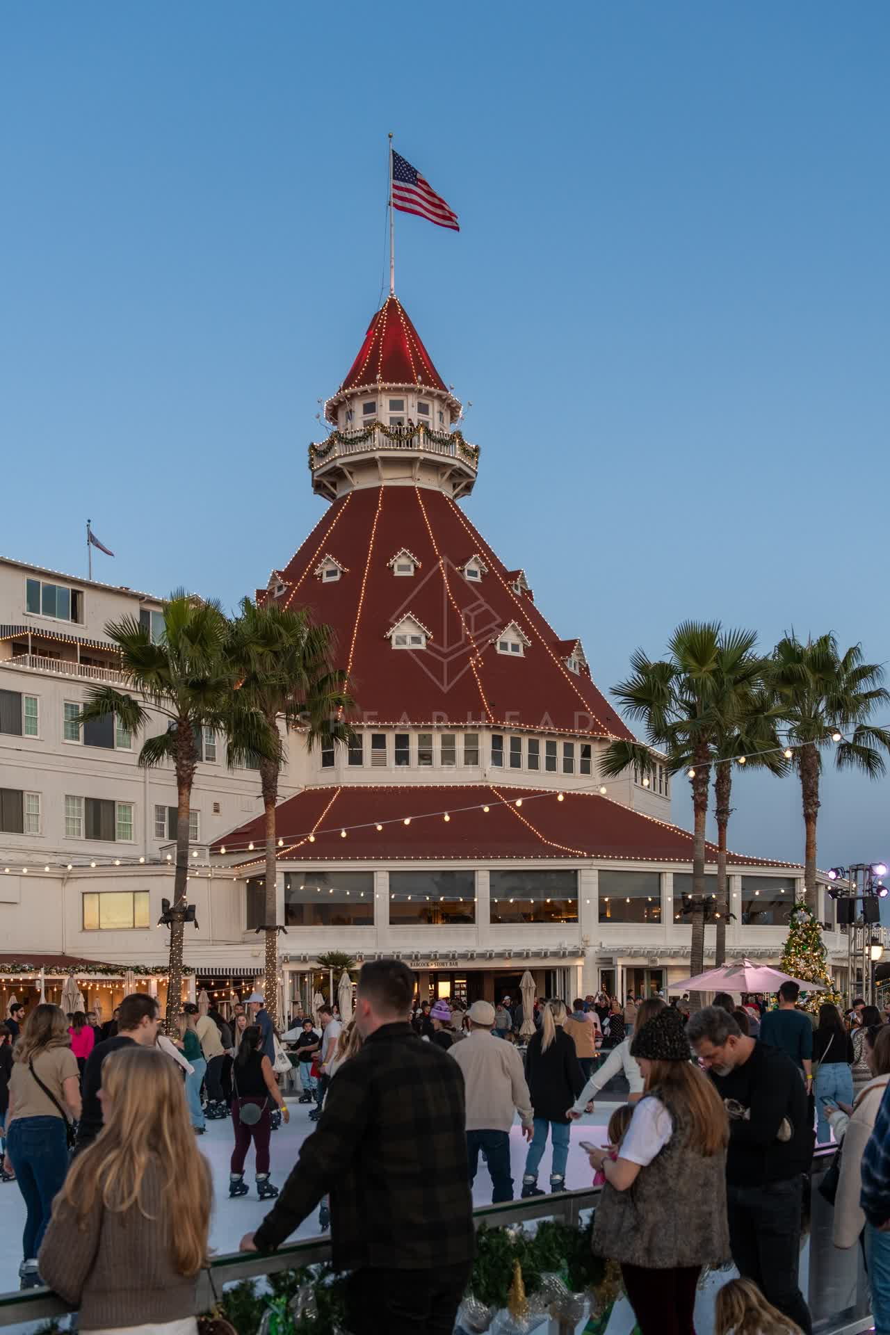 The downtown streets, palm trees and the buildings at Coronado Beach, with a crowd gathered.