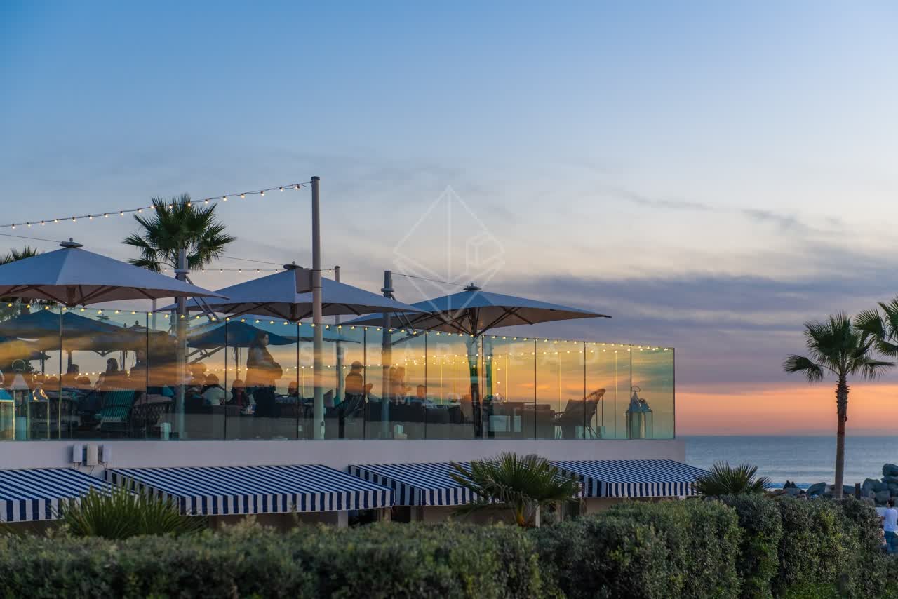 The beach, palm trees and the ocean at Coronado Beach, with people eating outside.