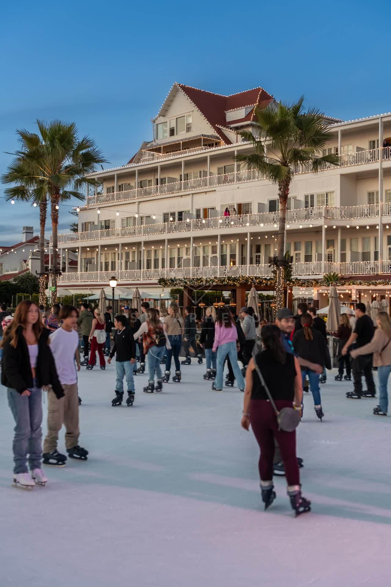The downtown streets, palm trees and the buildings at Coronado Beach, with a crowd gathered.