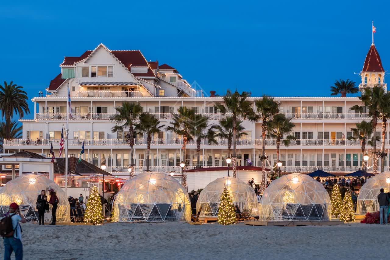 The beach, palm trees and the buildings at Coronado Beach, with a crowd gathered.