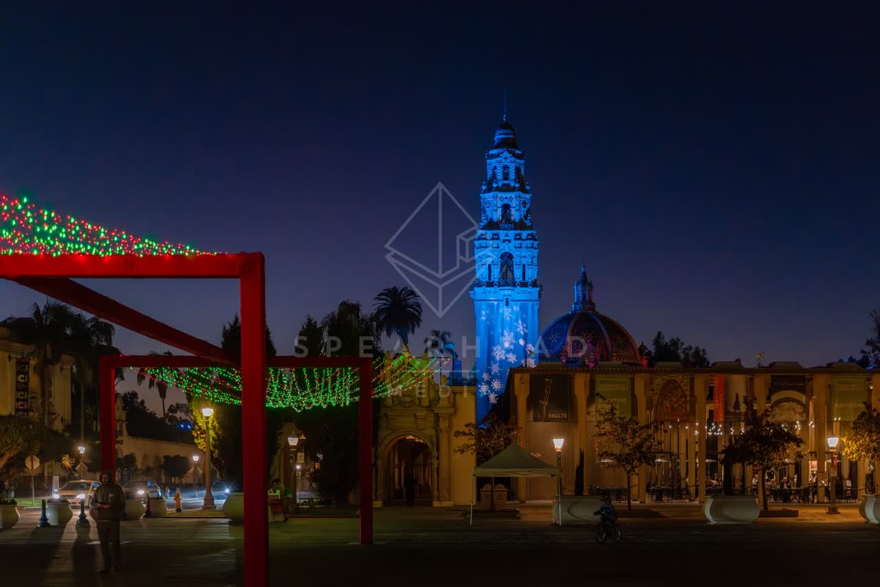 A park, palm trees and the buildings in Balboa Park, with a crowd gathered.