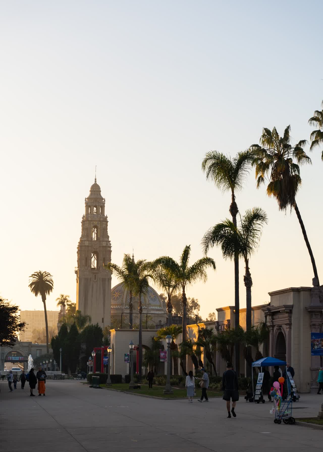 A park, palm trees and the buildings in Balboa Park, with people walking.
