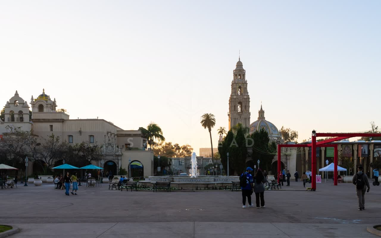 A park, palm trees and the buildings in Balboa Park, with people walking.