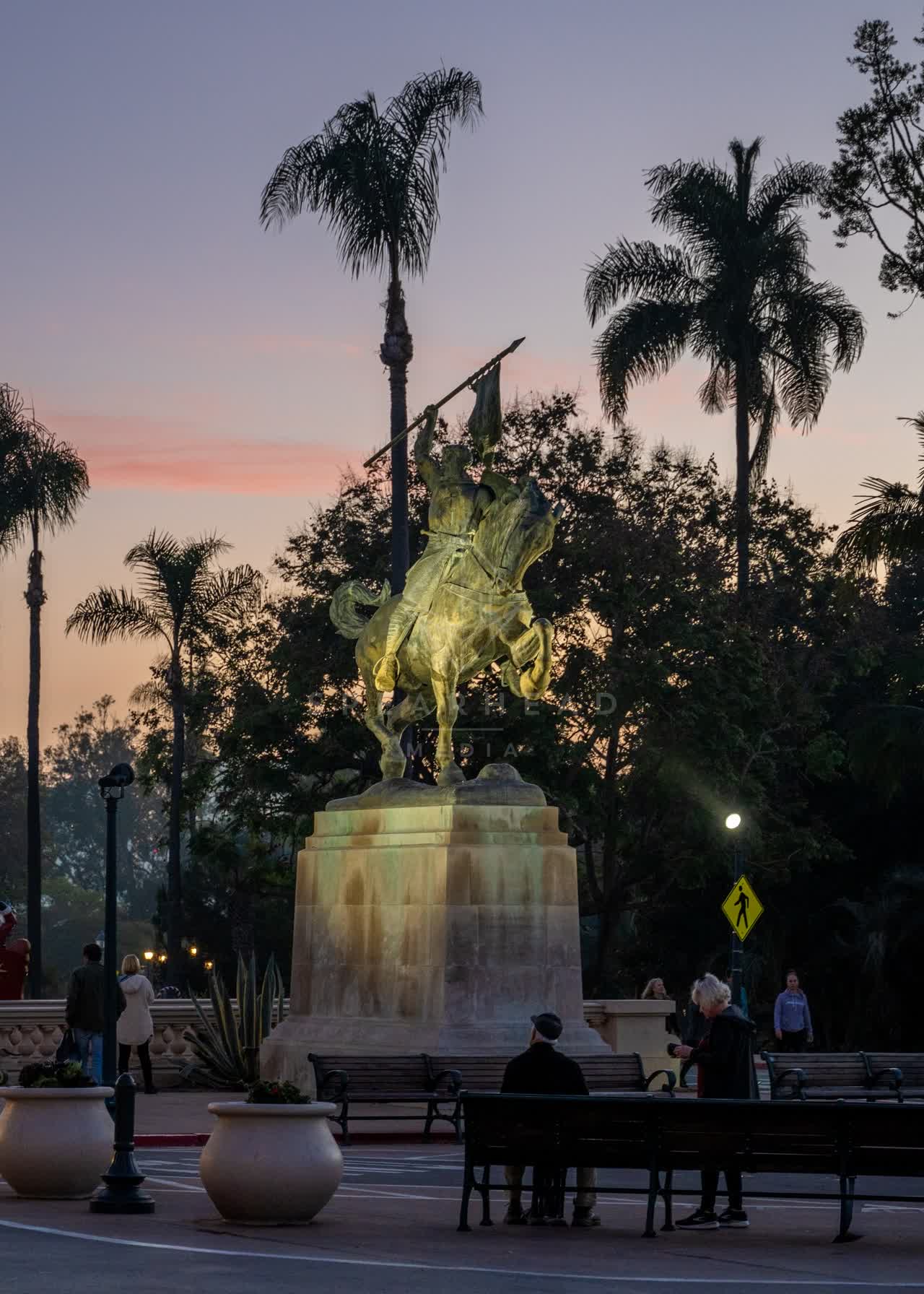 A park, palm trees and open country in Balboa Park, with people walking.
