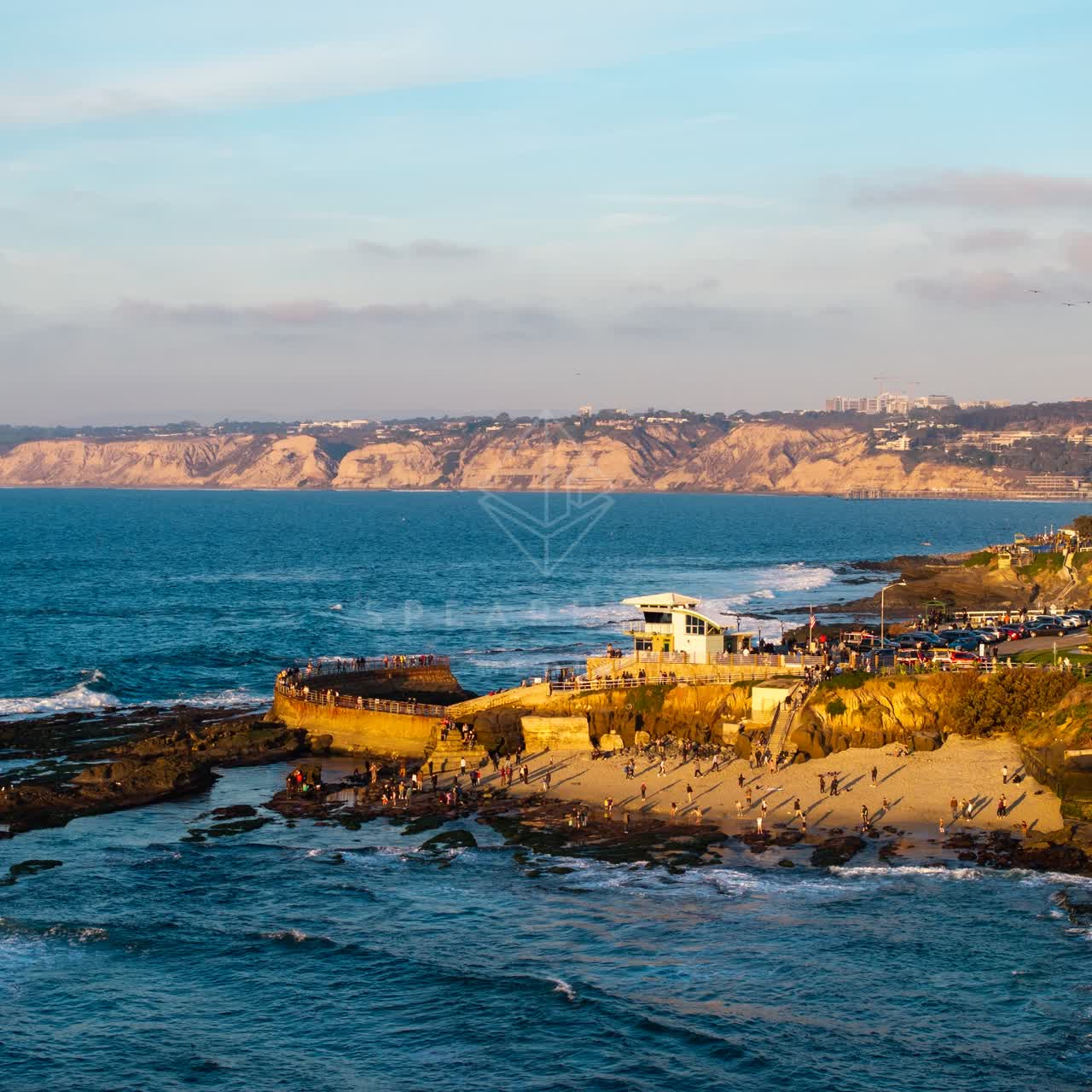 Aerial view of the cliffs, the ocean and the beach at La Jolla Cove, with a crowd gathered.