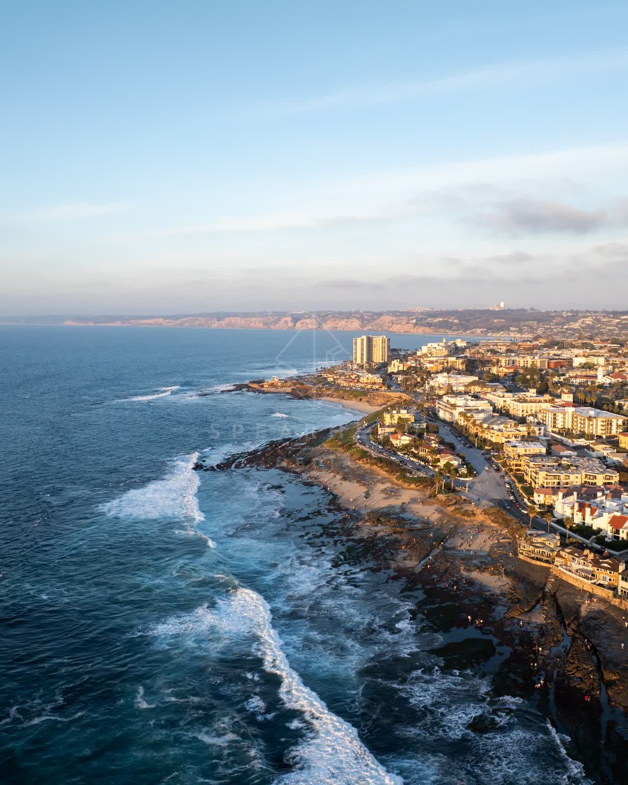 Aerial view of the cliffs, the surf and the ocean at La Jolla Cove.