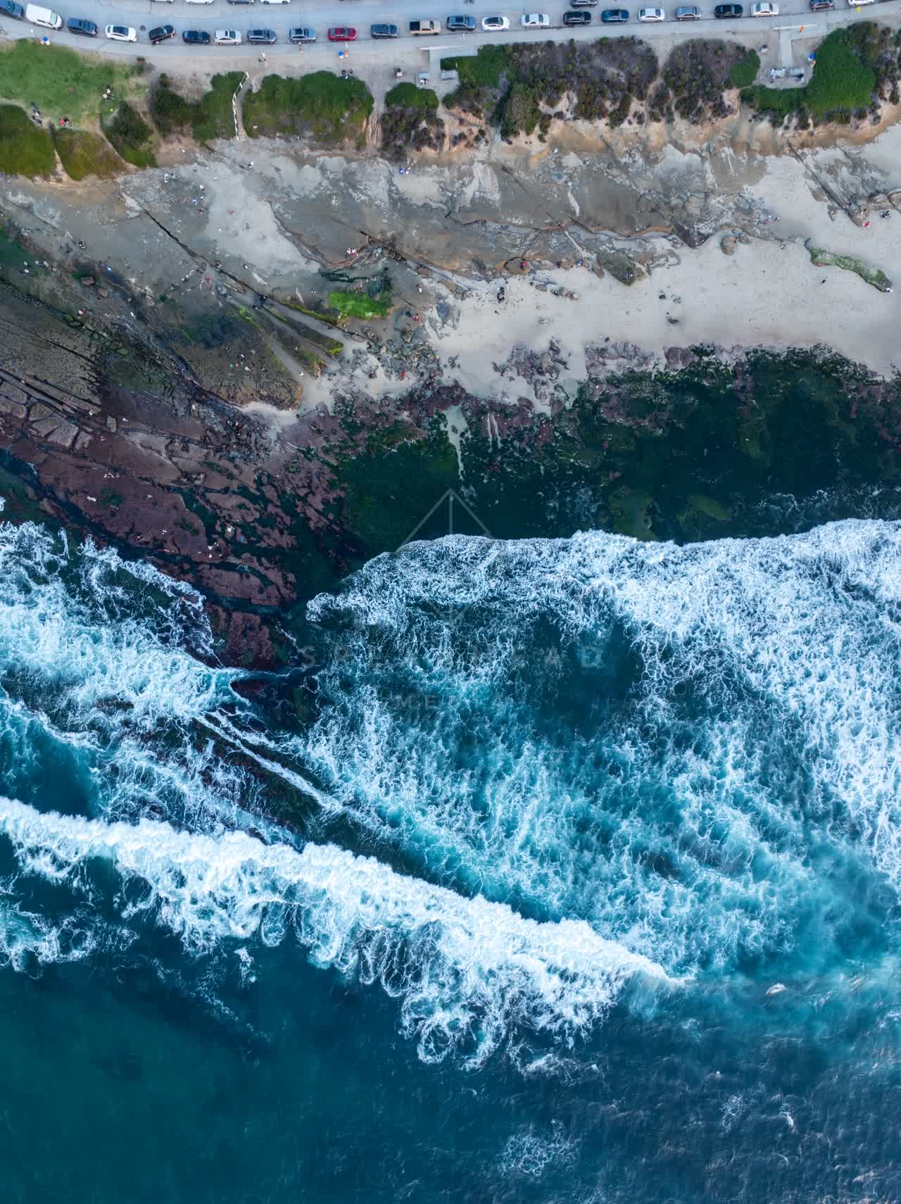 Aerial view of the cliffs, the surf and the ocean at La Jolla Cove.