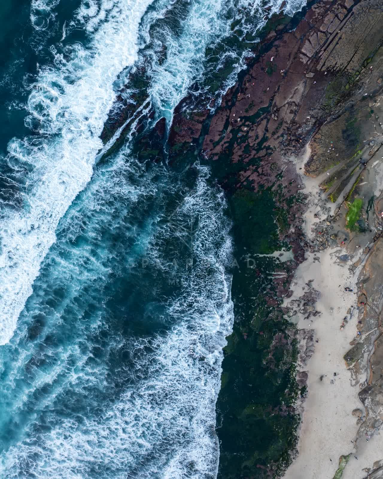 Aerial view of the cliffs, the surf and the ocean at La Jolla Cove.