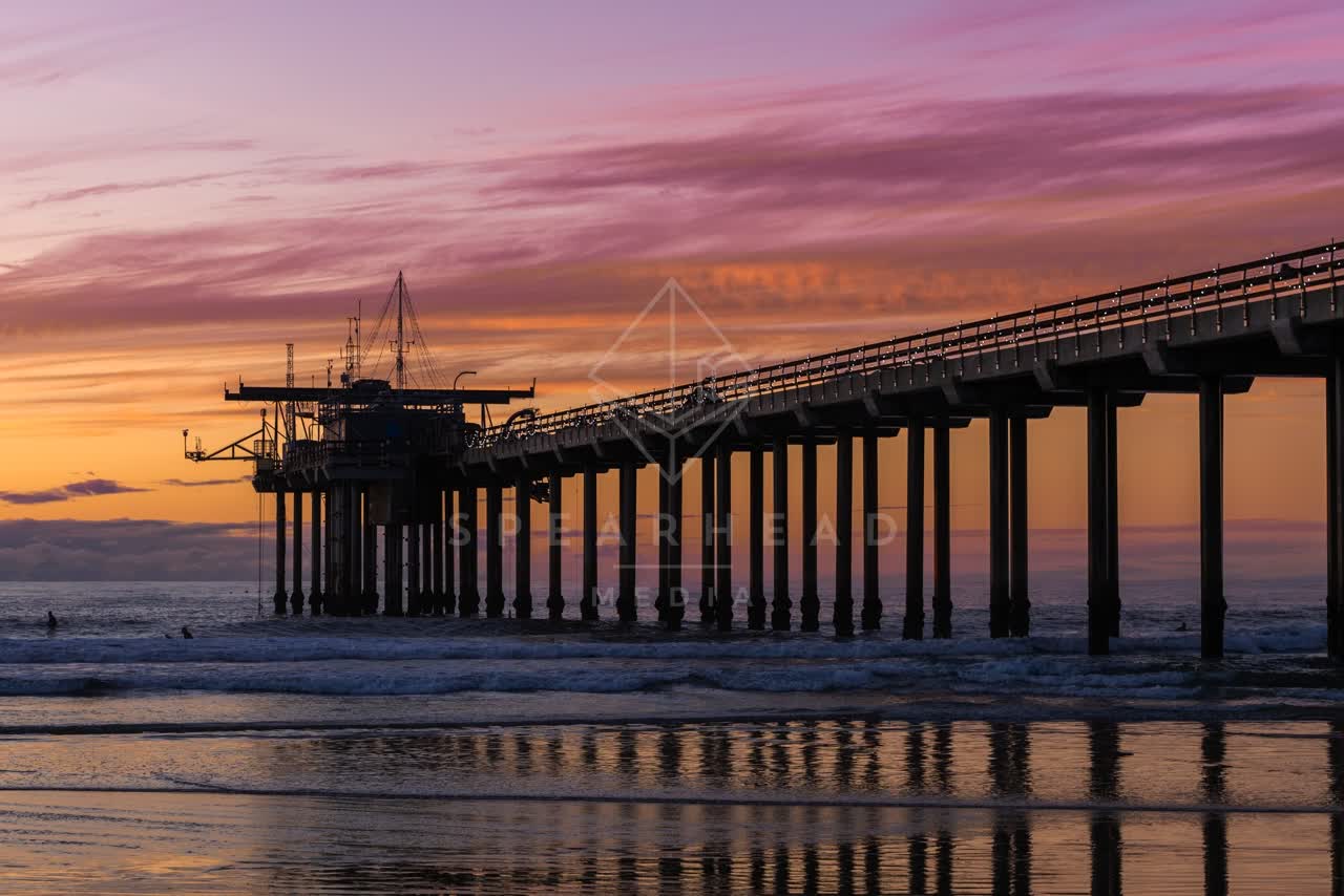 View from the water of the beach, the surf and the pier at La Jolla Shores, with surfers out.