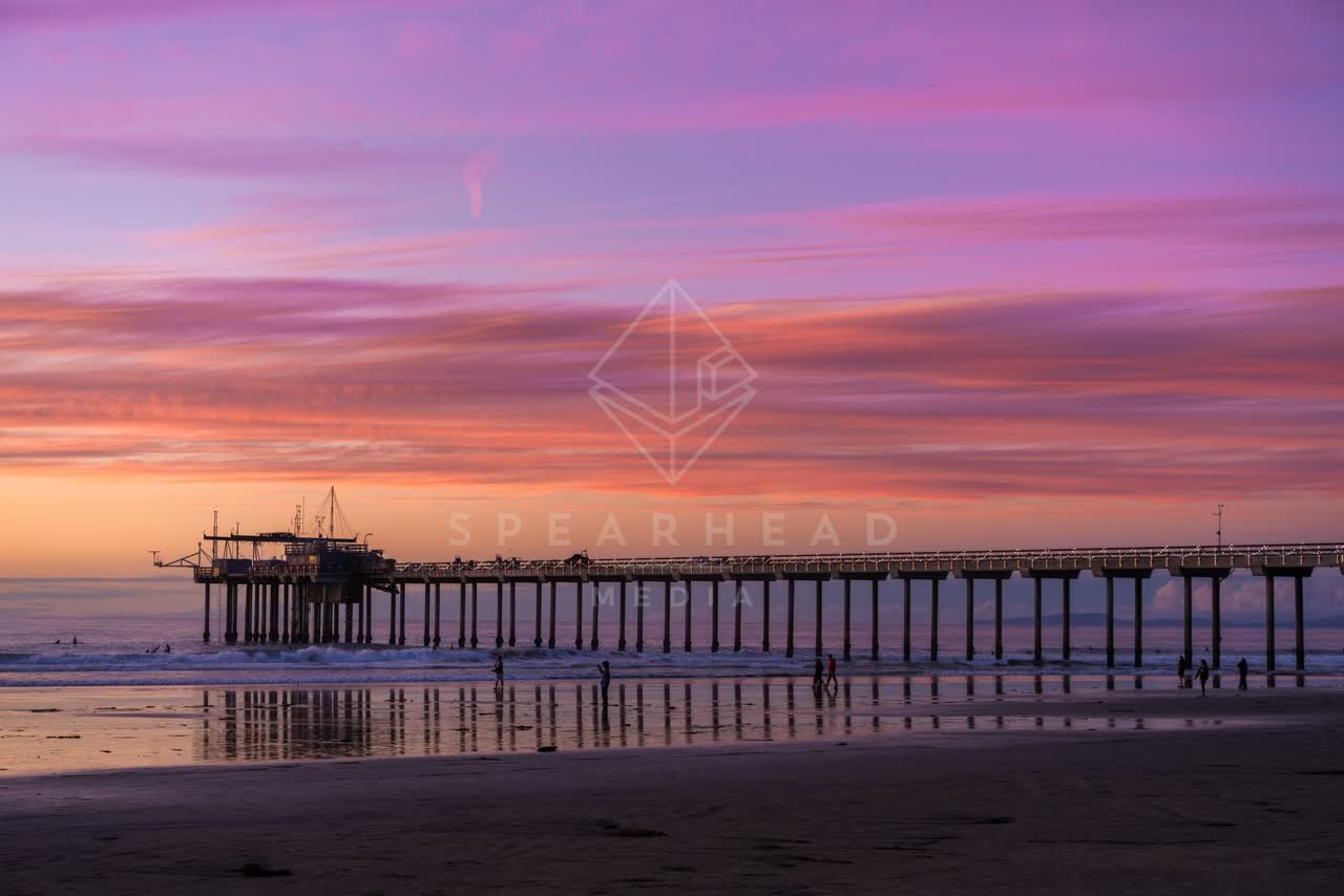 The beach, the surf and the pier at La Jolla Shores, with people walking.