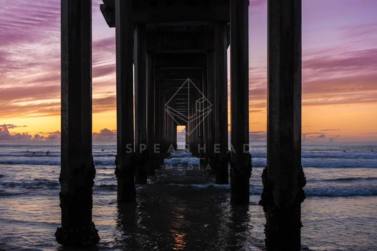 View from the water of the beach, the surf and the pier at La Jolla Shores, with surfers out.