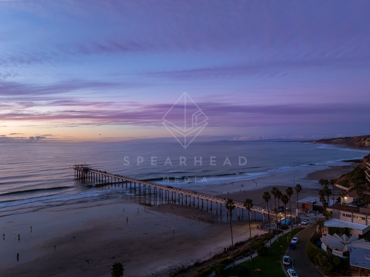 Aerial view of the beach, the surf and the pier at La Jolla Shores, with people walking.