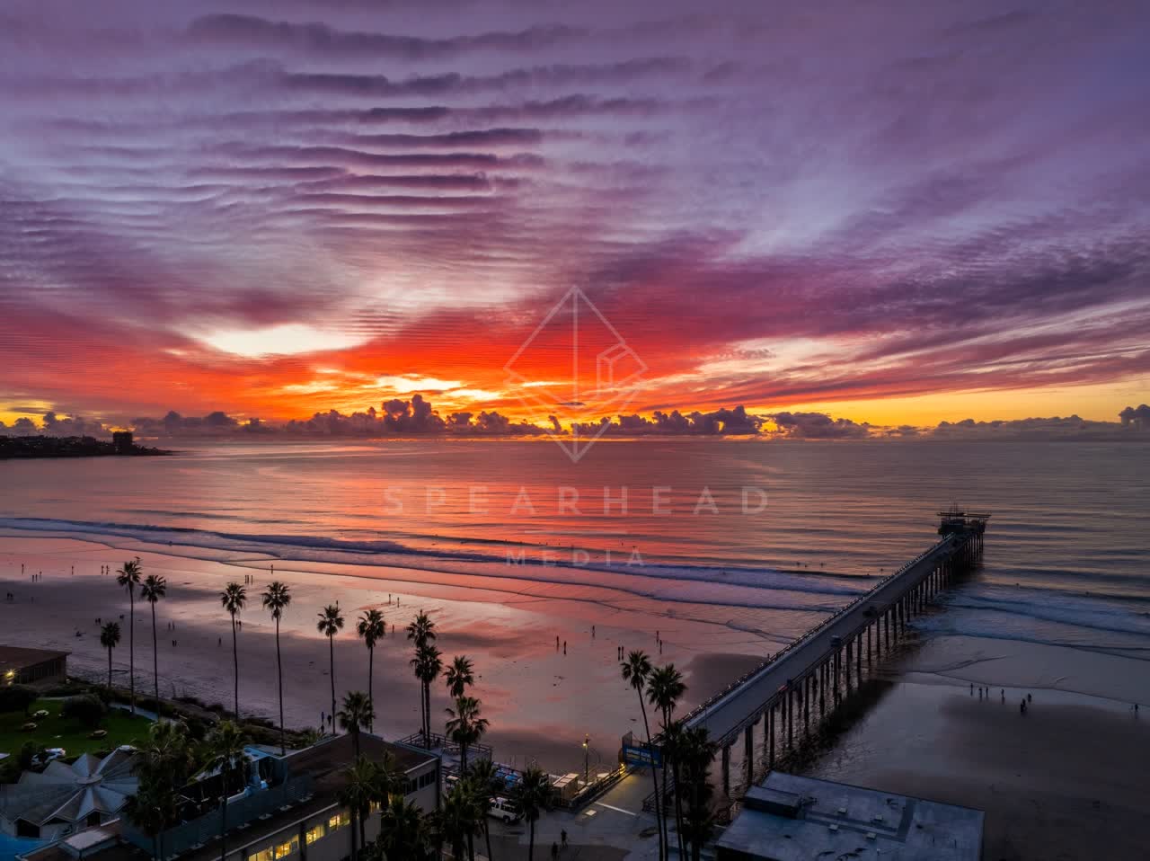Aerial view of the beach, the surf and the pier at La Jolla Shores, with people walking.
