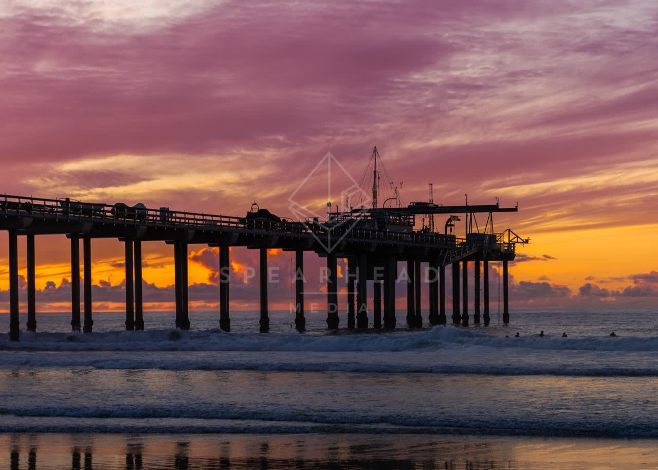 View from the water of the beach, the surf and the pier at La Jolla Shores, with surfers out.
