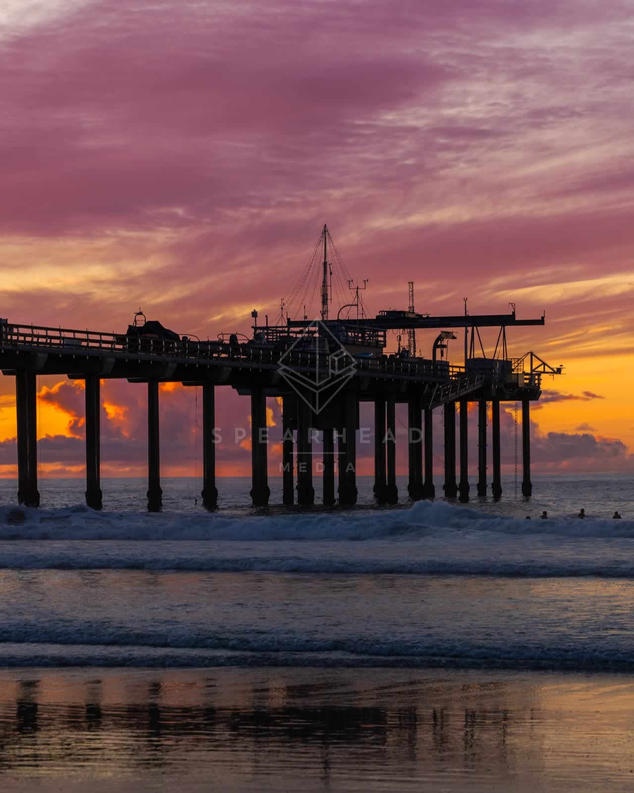 View from the water of the beach, the surf and the pier at La Jolla Shores, with swimmers in the water.