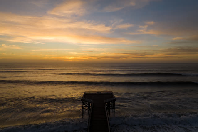 Low aerial view of the beach, the surf and the pier in Pacific Beach.
