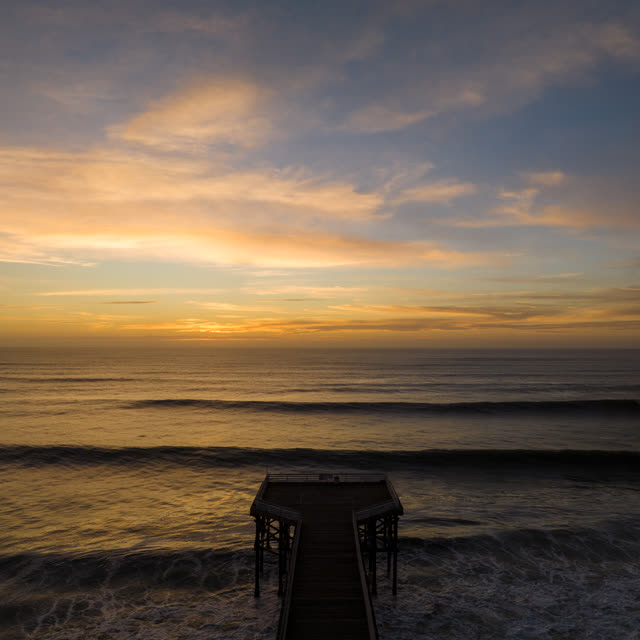Low aerial view of the beach, the surf and the pier in Pacific Beach.