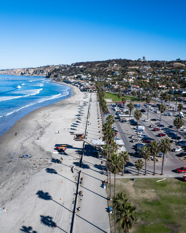 Aerial view of the beach, the surf and the pier at La Jolla Shores, with people walking.