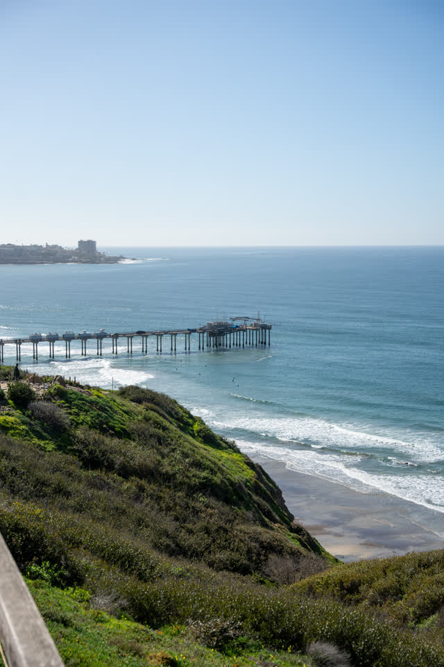 Elevated view of the cliffs, the surf and the pier at La Jolla Shores.