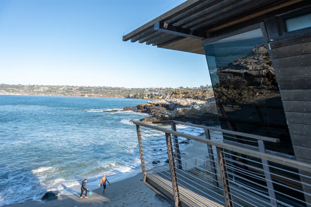 Elevated view of the cliffs, the ocean and the buildings at La Jolla Cove, with people walking.