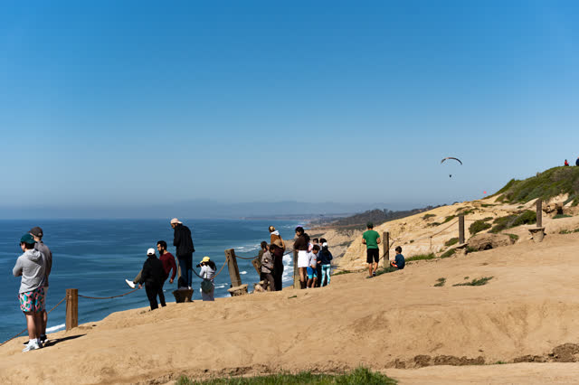 Elevated view of the cliffs, the ocean and open country at Torrey Pines, with a crowd gathered.