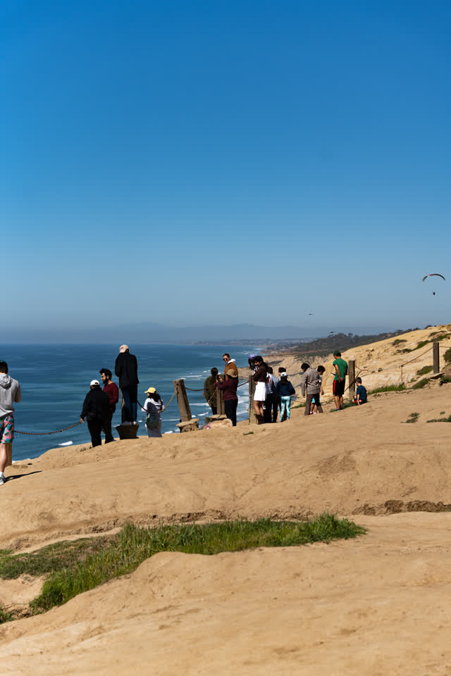 Elevated view of the cliffs, the ocean and open country at Torrey Pines, with people walking.