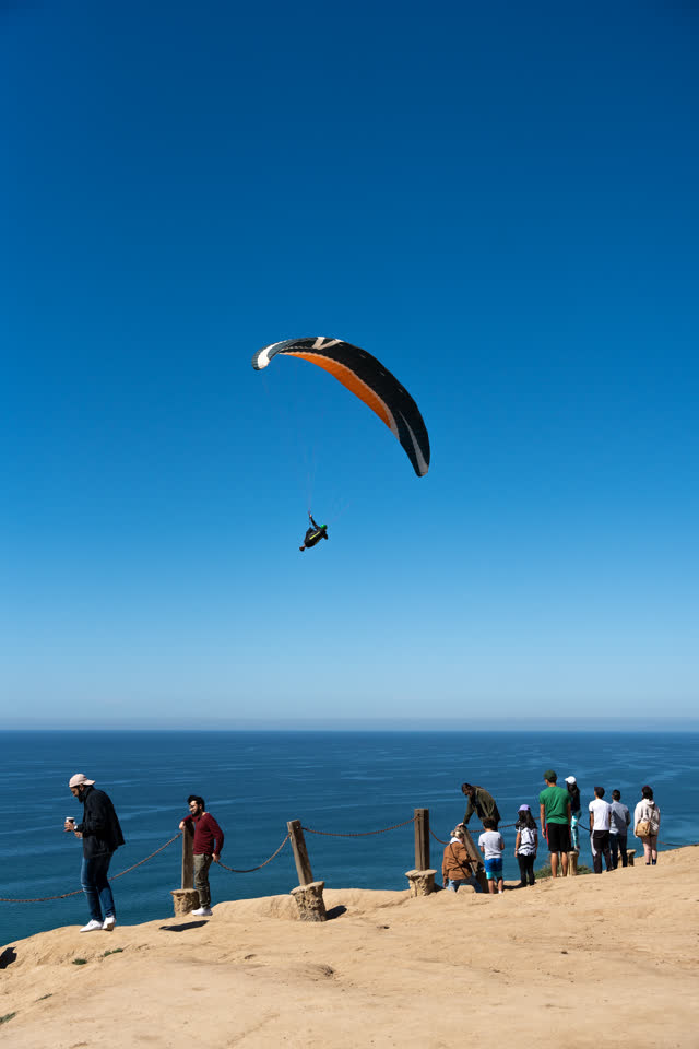 Elevated view of the cliffs, the ocean and open country at Torrey Pines, with a crowd gathered.