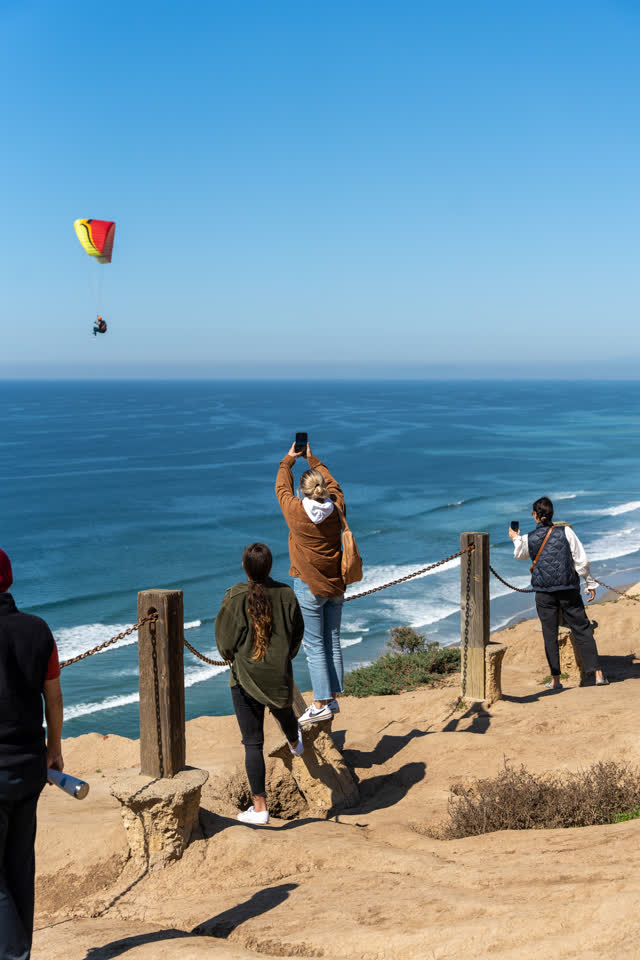 Elevated view of the cliffs, the ocean and the beach at Torrey Pines, with a crowd gathered.