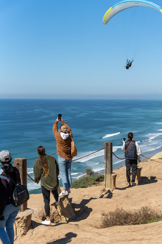 Elevated view of the cliffs, the ocean and open country at Torrey Pines, with a crowd gathered.