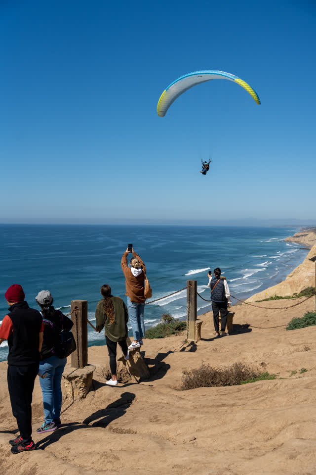 Elevated view of the cliffs, the surf and the ocean at Torrey Pines, with a crowd gathered.