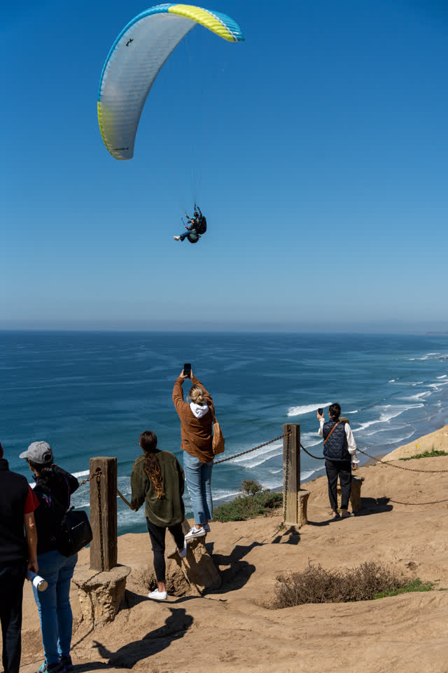 Elevated view of the cliffs, the surf and the ocean at Torrey Pines, with a crowd gathered.
