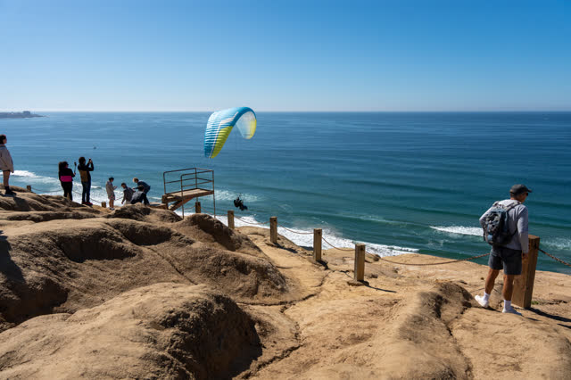 Elevated view of the cliffs, the ocean and open country at Torrey Pines, with a crowd gathered.