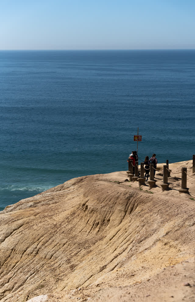Elevated view of the cliffs, the ocean and open country at Torrey Pines, with people walking.