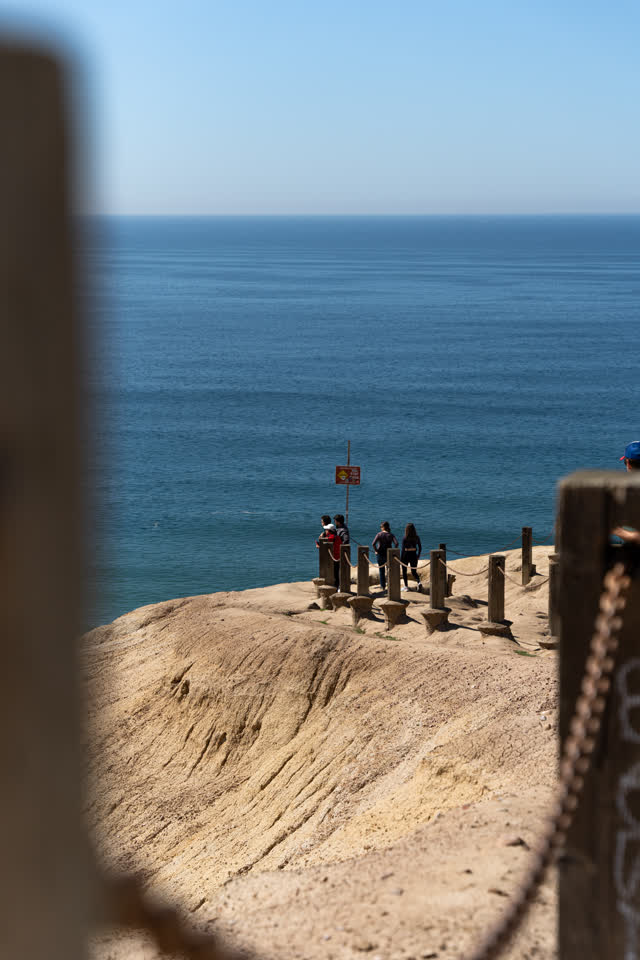 Elevated view of the cliffs, the ocean and open country at Torrey Pines, with people walking.