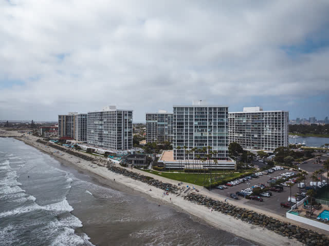 Aerial view of the beach, palm trees and the ocean at Coronado Beach, with people walking.