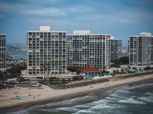 Aerial view of the beach, boats and palm trees at Coronado Beach, with people walking.