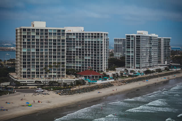 Aerial view of the beach, the surf and palm trees at Coronado Beach, with people walking.