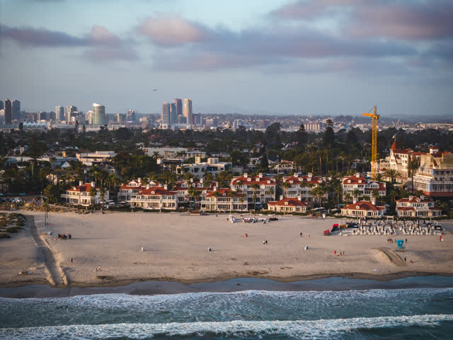Aerial view of the beach, the surf and the skyline at Coronado Beach, with people walking.