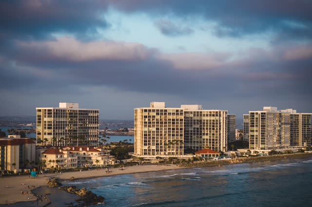 Aerial view of the beach, palm trees and the ocean at Coronado Beach, with people walking.