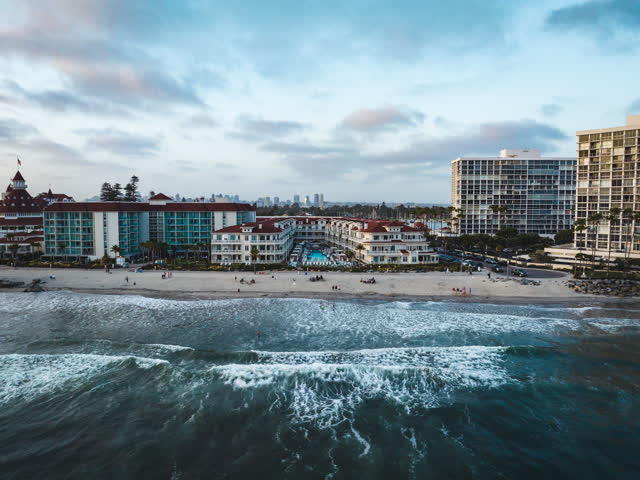 Aerial view of the beach, the surf and the skyline at Coronado Beach, with people walking.