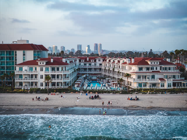Low aerial view of the beach, the surf and the skyline at Coronado Beach, with people walking.
