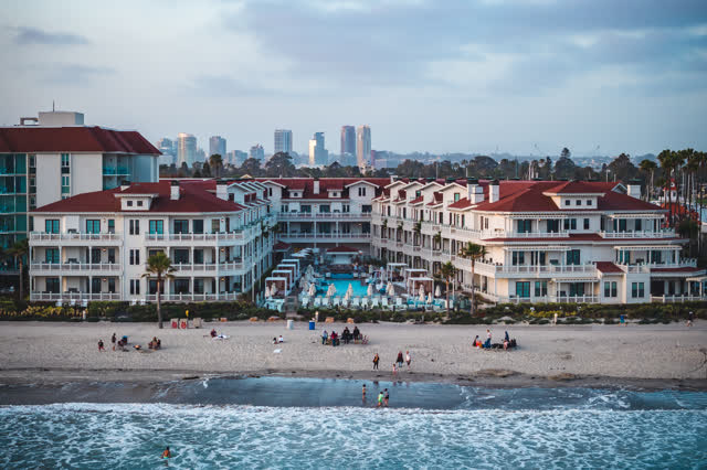 Low aerial view of the beach, the surf and the skyline at Coronado Beach, with people walking.