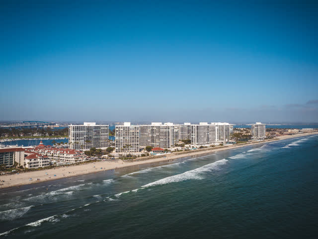 Aerial view of the beach, the surf and the bridge at Coronado Beach, with people walking.