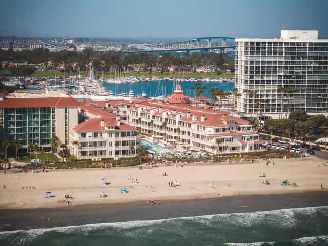 Aerial view of the beach, the bridge and boats at Coronado Beach, with people walking.