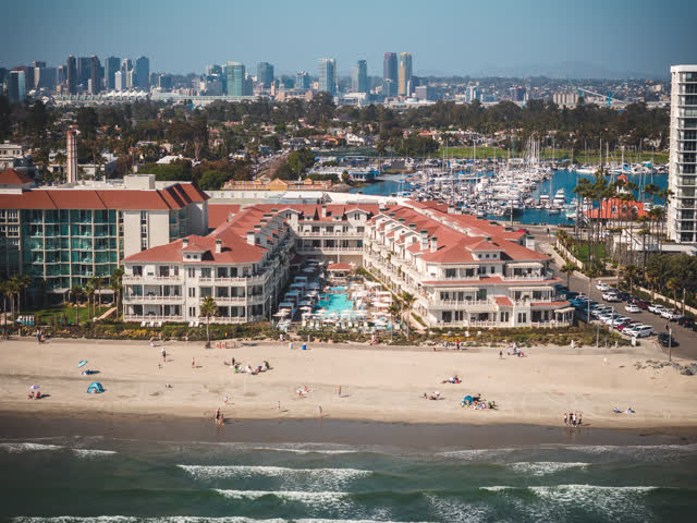 Aerial view of the beach, the skyline and boats at Coronado Beach, with people walking.
