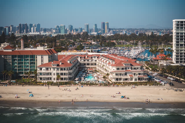 Aerial view of the beach, the skyline and boats at Coronado Beach, with people walking.