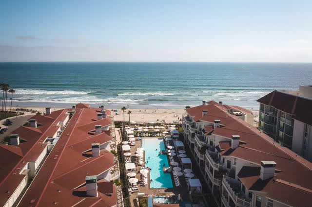 Aerial view of the beach, palm trees and the ocean at Coronado Beach, with swimmers in the water.